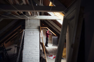 Rodent removal expert measuring attic space to locate potential rat entry points.