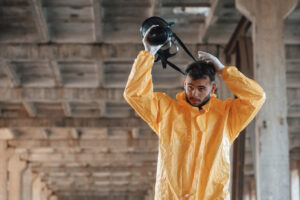 Pest control expert removing gas mask after treating rat-infested structure.